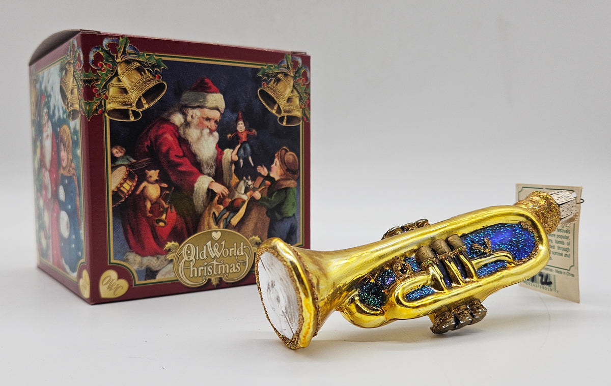 Old World Christmas Trumpet – Purple ornament #38019 – ornament alongside photographed packaging